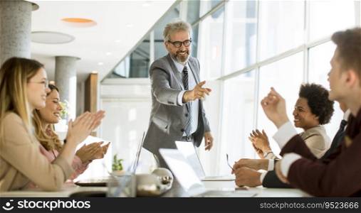 Mature businessman explaining strategy to group of multiethnic business people while working on new project in the office