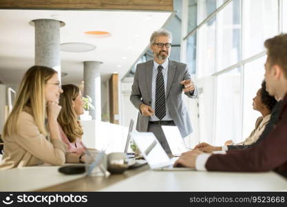 Mature businessman explaining strategy to group of multiethnic business people while working on new project in the office