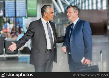Mature businessman gesturing while talking to business partner in airport