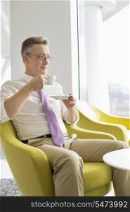 Mature businessman having coffee in lobby at office