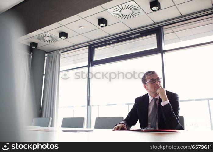 Mature businessman listening to meeting in board room