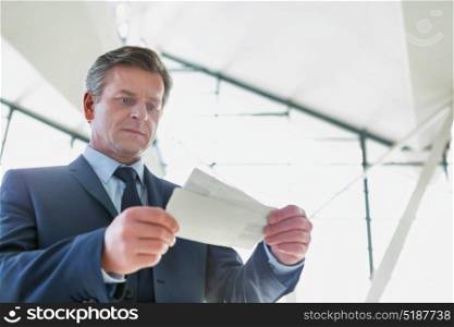 Mature businessman looking at his boarding pass in airport