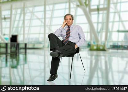 mature businessman on a chair, isolated on white
