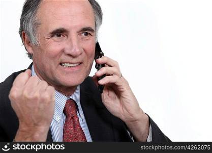 mature businessman on the phone clenching his fist