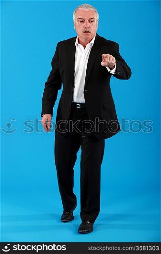 mature businessman pressing button against blue background
