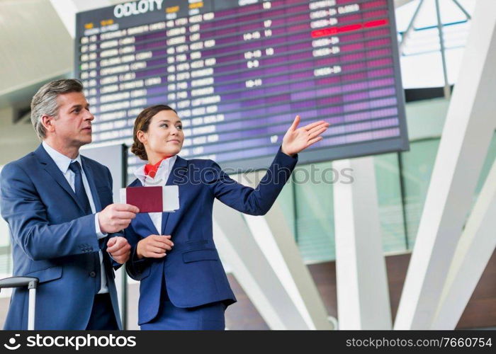 Mature businessman showing his boarding pass with the attractive airport staff