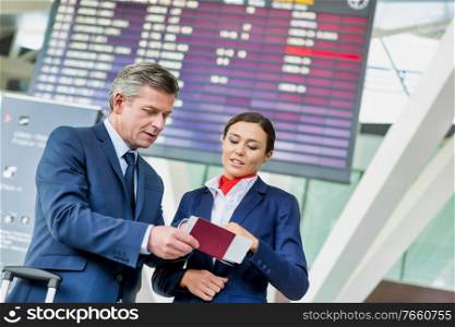Mature businessman showing his boarding pass with the attractive airport staff