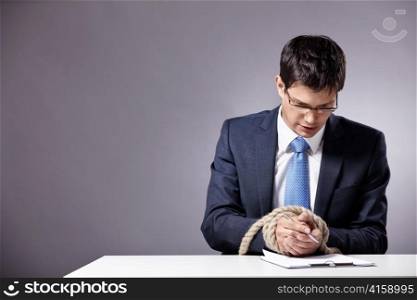 Mature businessman signs a document with tied hands