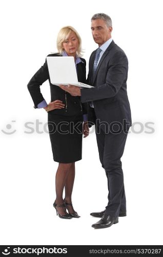 mature businessman standing with laptop and female counterpart