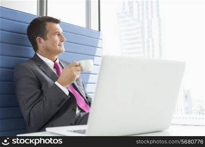 Mature businessman taking coffee break in office