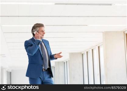 Mature businessman talking on mobile phone in new office