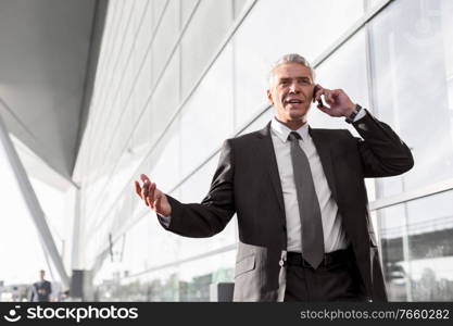 Mature businessman talking on smartphone in airport