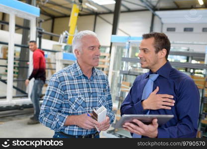 mature businessman talking to warehouse worker