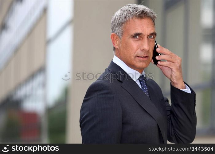 Mature businessman using a cellphone outside