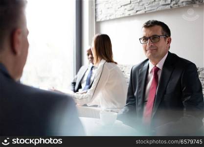 Mature businessman with colleagues in office cafeteria