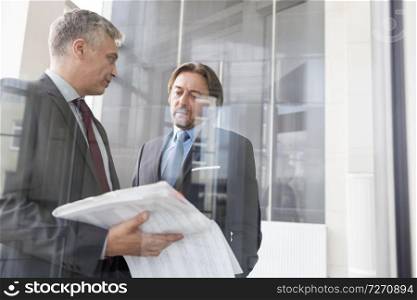 Mature businessmen discussing over document in new office