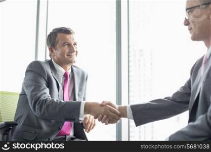 Mature businessmen shaking hands in office