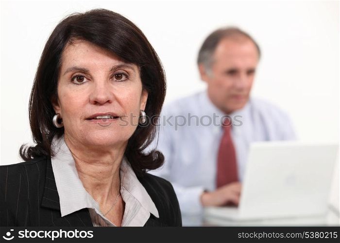 Mature businesswoman and man using a laptop