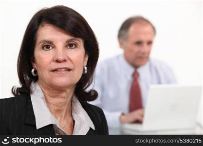 Mature businesswoman and man using a laptop