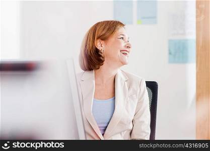 Mature businesswoman laughing at office desk