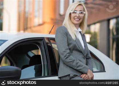 Mature businesswoman leaning on car outdoors