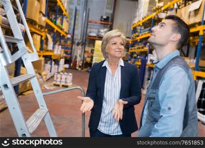 mature businesswoman with worker in warehouse