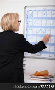 Mature businesswoman writing on a wall planner