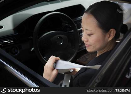 Mature businesswomen in car fastening seatbelt.