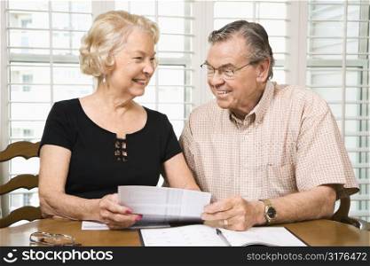 Mature Caucasian couple looking at their bills.