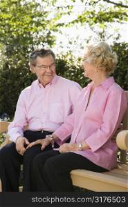 Mature Caucasian couple sitting together on bench.