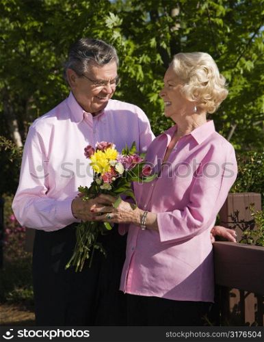 Mature Caucasian man giving mature Caucacsian woman flowers.
