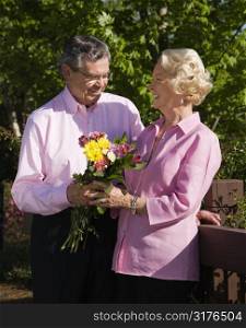 Mature Caucasian man giving mature Caucacsian woman flowers.