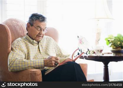 Mature Caucasian man sitting in chair reading a book.