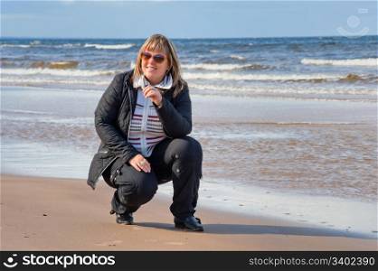 Mature chubby woman relaxing at the Baltic sea in autumn day.