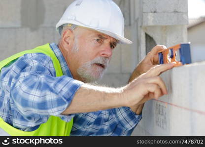 mature construction worker using level