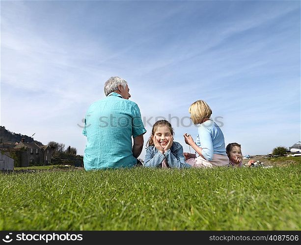 mature couple & children relax on grass