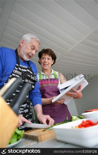 Mature couple cooking with cookbook