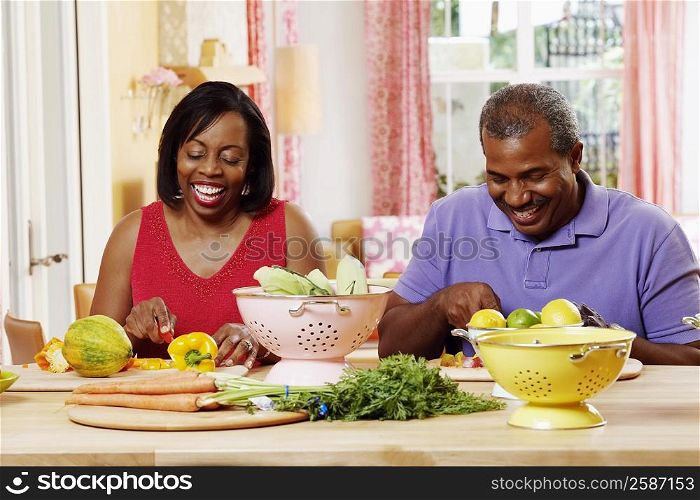 Mature couple cutting vegetables and smiling