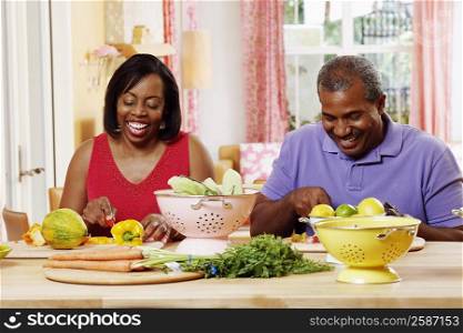 Mature couple cutting vegetables and smiling