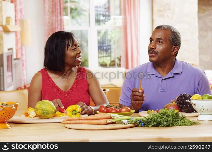 Mature couple cutting vegetables and talking