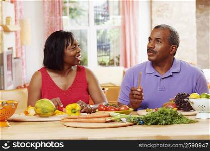 Mature couple cutting vegetables and talking