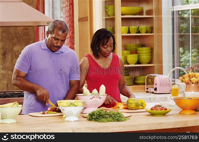 Mature couple cutting vegetables in the kitchen