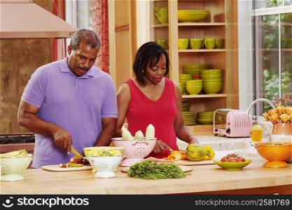 Mature couple cutting vegetables in the kitchen