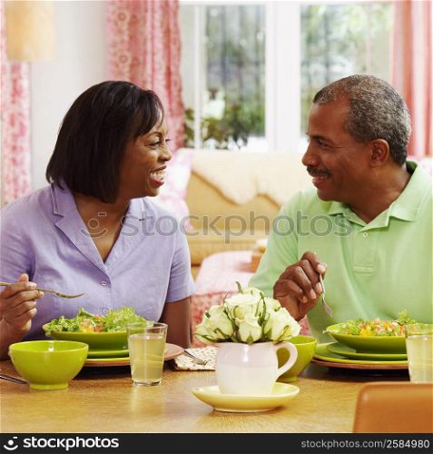 Mature couple eating salad and looking at each other