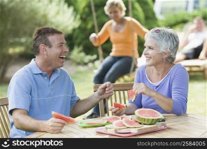 Mature couple eating watermelon slices in a lawn