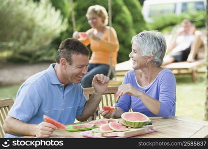 Mature couple eating watermelon slices in a lawn