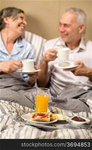 Mature couple enjoying romantic breakfast at hotel room