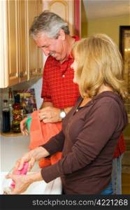 Mature couple having fun doing dishes together.