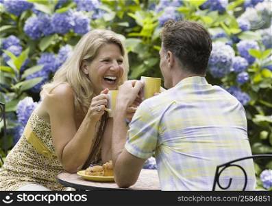 Mature couple having tea in a lawn and laughing