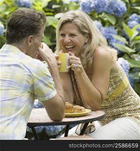 Mature couple having tea in a lawn and laughing